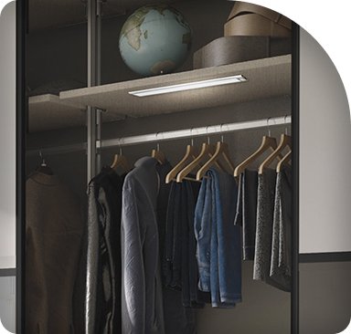 Fitted dressing room with a lit hanging rail and shelf above